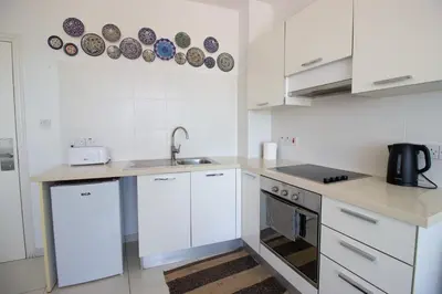 a kitchen with white cabinets and a sink at Seafront Stylish Apt, Protaras in Protaras