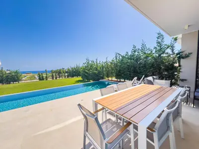 a dining room with a table and chairs next to a swimming pool at Azure Breeze Villa - Roof Garden & Sea Views in Protaras