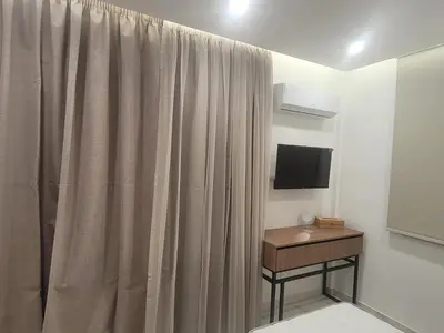 a room with a curtain and a table with a television at IOLENA Seaview Apartment in Pyla