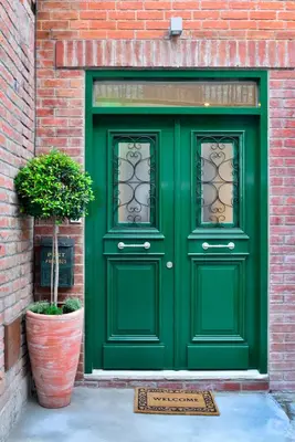 a green door on a brick building with a potted plant at Vasilikis House in Kalopanayiotis