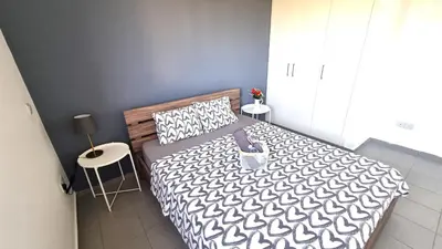 a bedroom with a bed with a black and white comforter at Beachside Comfort - 2Br Apt,5 Min to the Beach in Larnaka