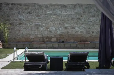 two chairs and a swimming pool with a stone wall at Villa To Palati with Private Pool Anogyra in Anoyira