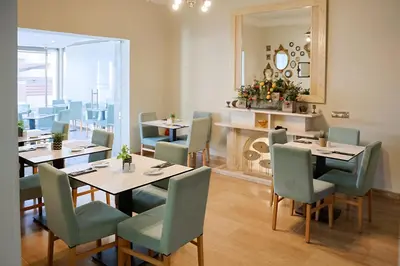 a dining room with tables and chairs and a mirror at Mikes Kanarium City Hotel in Larnaka