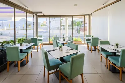 a restaurant with tables and chairs and windows at Mikes Kanarium City Hotel in Larnaka