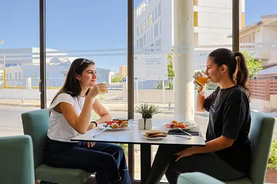 two women sitting at a table drinking wine at Mikes Kanarium City Hotel in Larnaka