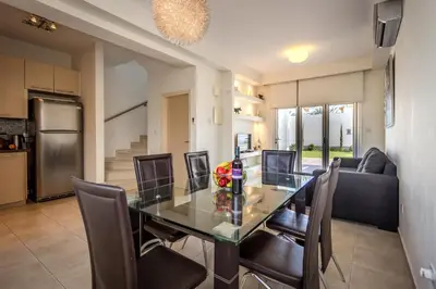 a dining room and kitchen with a glass table and chairs at Villa Nora in Protaras