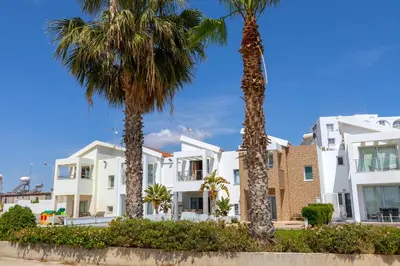 a row of white apartment buildings with palm trees at Villa Nora in Protaras