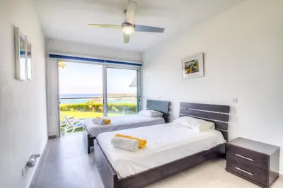 two beds in a bedroom with a view of the ocean at Beachfront Trident in Protaras