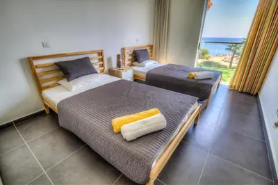 two beds in a room with a view of the ocean at Beachfront Trident in Protaras