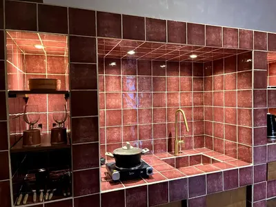 a kitchen with brown tiled walls and a pot on a stove at Stin Avli tou Pavlou Guest House in Omodos