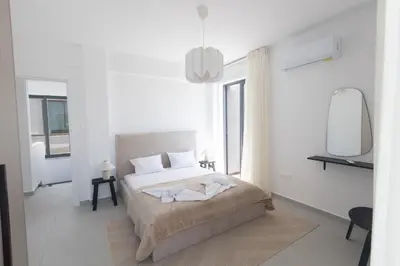 a white bedroom with a bed and a mirror at Semeli Villa 8 in Protaras