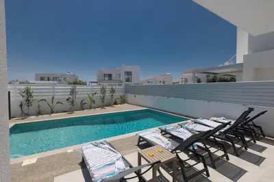 a patio with chairs and a swimming pool on a building at Semeli Villa 8 in Protaras