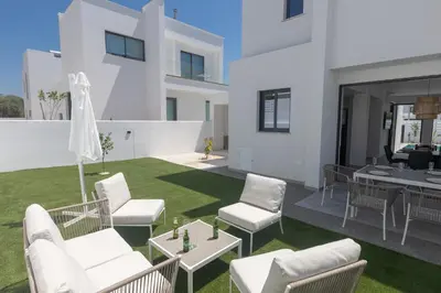 a patio with white chairs and tables on a lawn at Semeli Villa 8 in Protaras