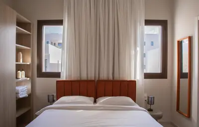 a bed in a bedroom with two windows at LIV & CO Suites & Villas in Voroklini