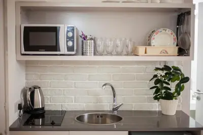 a kitchen with a sink and a microwave on a shelf at Operetta House in Larnaka