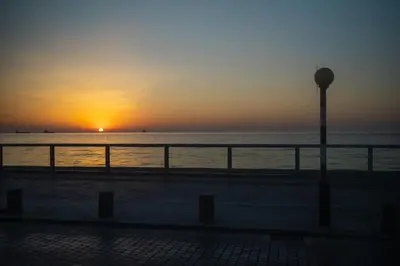 a sunset on the beach with a light pole at Maestro Sunrise View in Larnaka