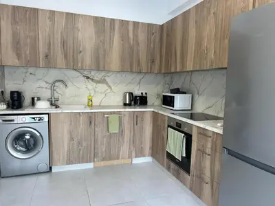 a kitchen with wooden cabinets and a washer and dryer at Limassol Urban Beach Retreat- 500m from the beach in Limassol