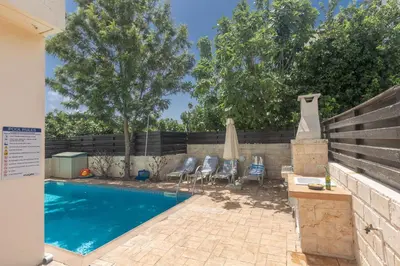 a swimming pool with four chairs and a umbrella at Protaras Orestiada Villa OV14 in Protaras