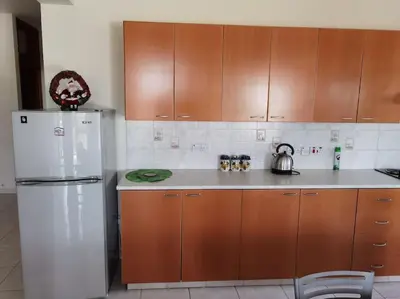 a kitchen with a white refrigerator and wooden cabinets at Lovely house apartment 2 bedrooms wiht nice view in Voroklini