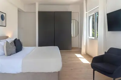 a bedroom with a bed and a blue chair at Phaedrus Living City Breeze Residences Urbanity in Larnaka