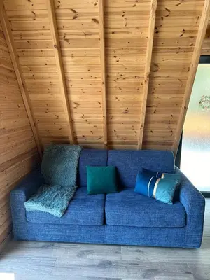 a blue couch with two pillows in a room at Warm Family Glamping Cabin with Kids Playground in Arakapas