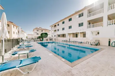 a swimming pool with chairs and a building at Apartment Anabelle in Paralimni