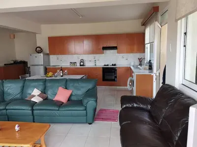 a living room with a blue couch and a kitchen at Lovely house apartment Oroklini in Voroklini