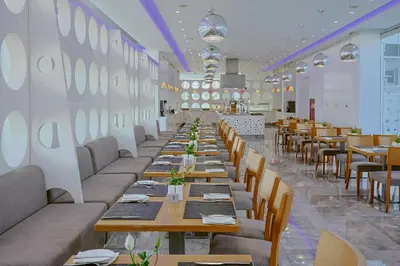 a long dining room with wooden tables and chairs at River Rock Hotel in Ayia Napa