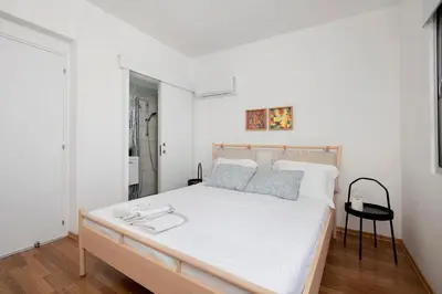 a bedroom with a white bed with a black chair at Amazing Two Bedroom Apartment in Larnaka