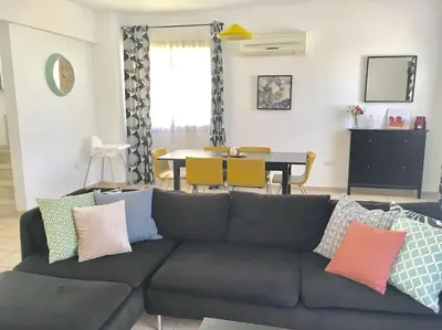 a living room with a gray couch with colorful pillows at Maison Diana - Tourism license 6990 in Protaras