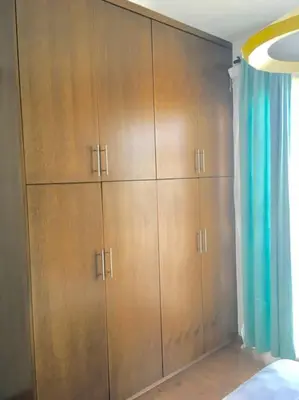 a bedroom with wooden cabinets and a blue curtain at Maison Diana - Tourism license 6990 in Protaras