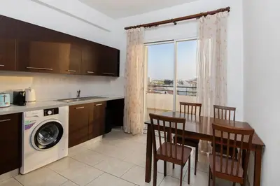 a kitchen with a table and a sink and a washing machine at City Center Top Floor Big Balcony 2BR Close to the Beach in Larnaka
