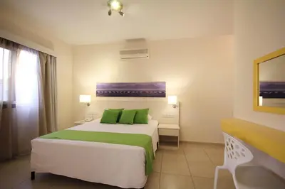 a bedroom with a large bed with green pillows at Sea CleoNapa Hotel in Ayia Napa
