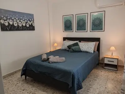 a bedroom with a bed with two lamps and pictures on the wall at Marina view seaside apartment in Larnaka