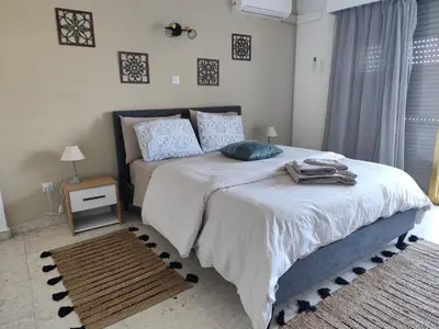 a bedroom with a bed with white sheets and blue pillows at Marina view seaside apartment in Larnaka