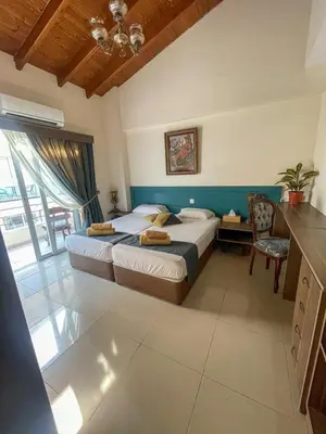 a bedroom with two beds and a table and a chair at DownTown Studios & Two-Bedrooms in Larnaka
