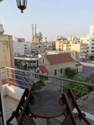 a balcony with two chairs and a table on a roof at DownTown Studios & Two-Bedrooms in Larnaka