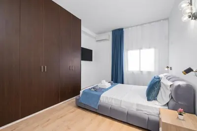 a bedroom with a bed and wooden cabinets and a desk at Paradise Apartment with Private Pool & Sea View in Larnaka