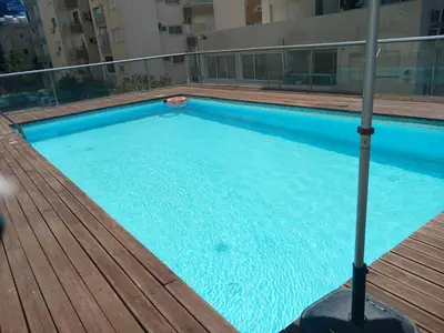 a large swimming pool with a wooden deck at Paradise Apartment with Private Pool & Sea View in Larnaka