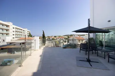a patio with an umbrella and chairs on a building at Beachside 1-bed with huge veranda in Protaras