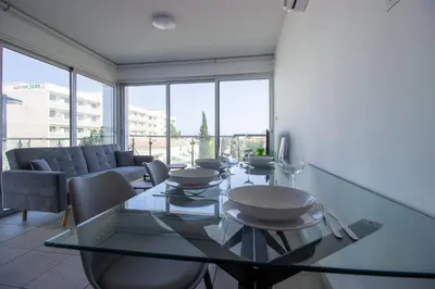 a dining room with a glass table and a couch at Beachside 1-bed with huge veranda in Protaras