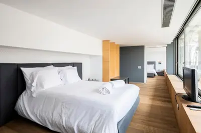 a bedroom with a large white bed and a flat screen tv at The Loft Penthouse in the Heart of City Center in Nicosia