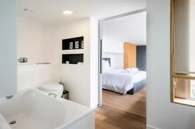 a white bathroom with a bed and a mirror at The Loft Penthouse in the Heart of City Center in Nicosia