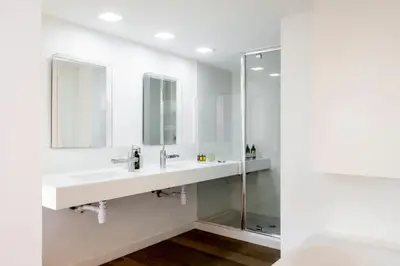 a white bathroom with two sinks and a shower at The Loft Penthouse in the Heart of City Center in Nicosia