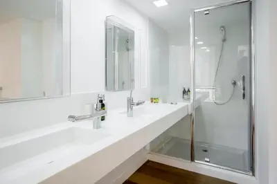 a white bathroom with two sinks and a shower at The Loft Penthouse in the Heart of City Center in Nicosia