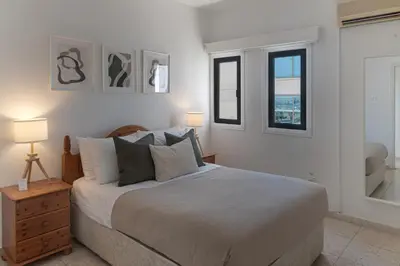 a white bedroom with a bed and two windows at Phaedrus Living Seaview Phinikoudes Flat in Larnaka