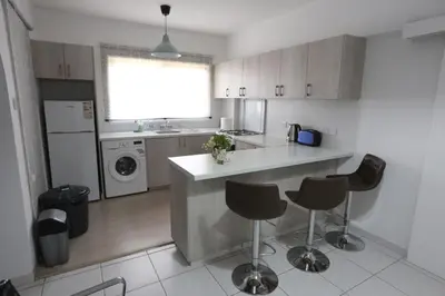 a kitchen with a counter and some chairs in it at Near the Beach Holiday Apartment in Limassol