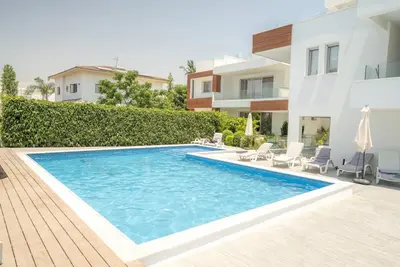 a swimming pool in front of a house at Hubstay Tamara Gardens 2 Bed Apt Suite with Pool in Livadhia