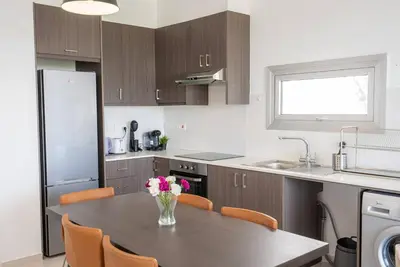 a kitchen with a table with a vase of flowers on it at Hubstay Tamara Gardens 2 Bed Apt Suite with Pool in Livadhia