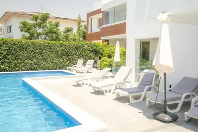 a group of chairs and an umbrella next to a swimming pool at Hubstay Tamara Gardens 2 Bed Apt Suite with Pool in Livadhia